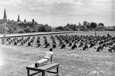 Men perform pushups on the lawn during army physical training at Georgetown during 1940s