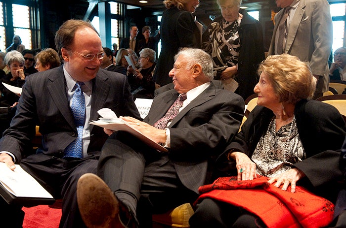 Rabbi Harold White sits in the audience with President John J. DeGioia and a woman in Gaston Hall.