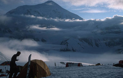 Francis Slakey stands in a camp in Denali National Park with snow covered mountain in background