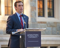 Danieal Feehan speaks at a lectern in front of White-Gravenor Hall at Georgetown