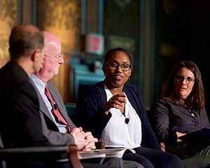 Rev. Matthew Carnes, S.J., Shaun Casey, Marcia Chatelain gesturing and Rabbi Rachel Gartner on stage in Gaston Hall