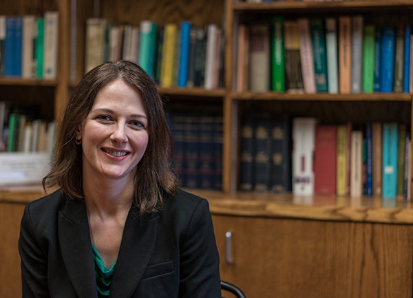 Erin Cline sits in her office with a bookcase filled with books behind her