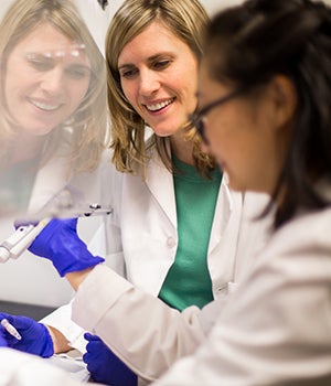 Professor Sarah Johnson looks on as student Emily Bai takes tests samples in the lab