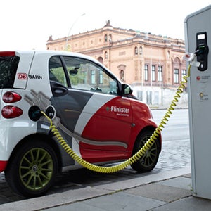 red and white electric car hooked up to charging station