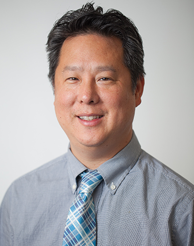 Headshot of Steve Park in gray patterned shirt and light blue, dark blue and white tie. 