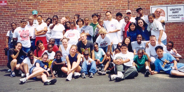 Steve Park poses outside in front of a brick building with a group of Little Lights students and volunteers.