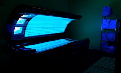 A photo of a glowing tanning bed in a darkened room.