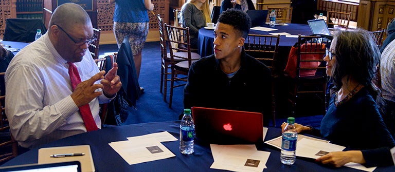 James Benton sits at a table talking to August Matthews and Lynn Nehemiah.