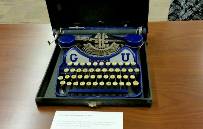 A blue and gray Corona Portable Typewriter from 1925 with a "G" and "U" on it.