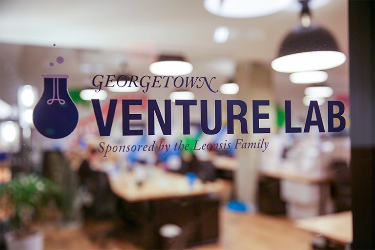 Glass window reads "Georgetown Venture Lab, Sponsored by Leonsis Family" that overlooks brightly lit workspace. 