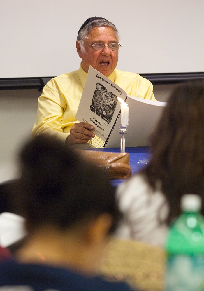 Rabbi Harold White sits and reads from a document during a religious ceremony.