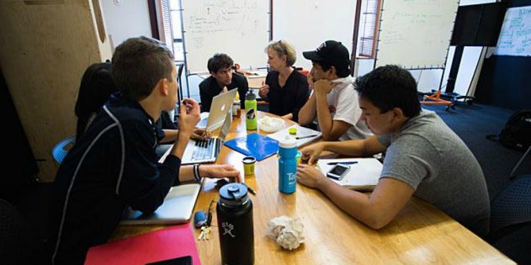 Arjun Dhillon, Maggie Little and others sit around a table in an office