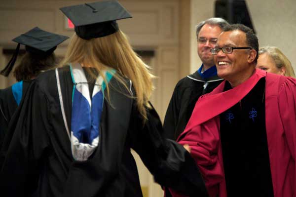 Edward Montgomery shakes hands with a student as others look on 