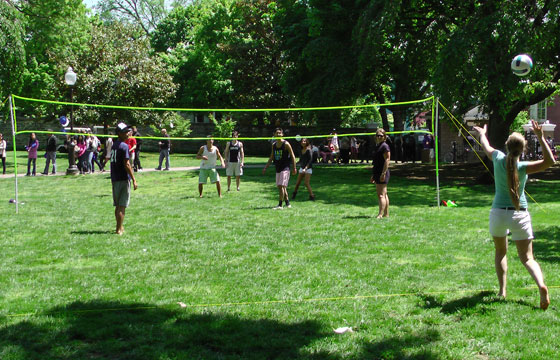 A students prepares to hit a volleyball thrown in the air over a net on Healy Lawn while others look on