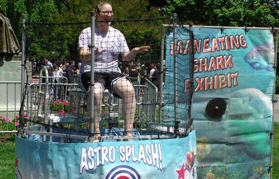 A student sits on a board behind a cage with a water tank underneath her