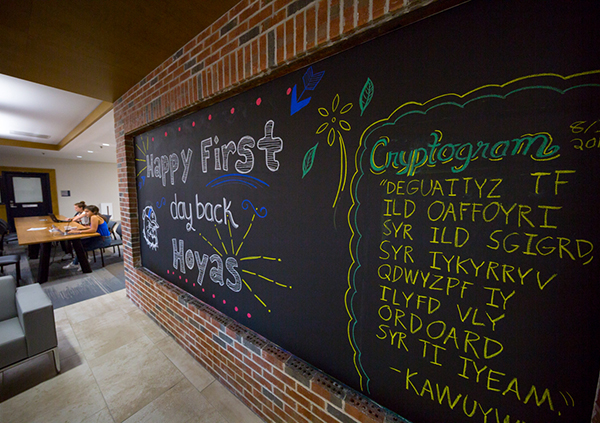 Colorful message on a chalkboard hangin on the wall wishing students "Happy First Day of Classes." 
