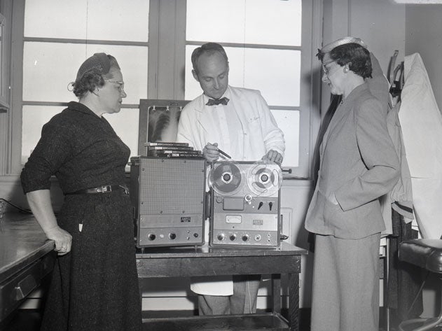 W. Proctor Harvey examines machine while two women look on