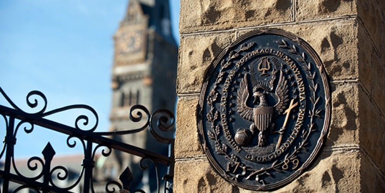 A view of the Healy Building's Clocktower from Healy Gates and a closeup of the seal mounted on the gate's stone column