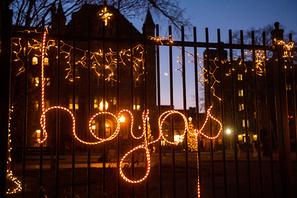 "Hoyas" spelled in Christmas lights on the front gates with Healy Hall in the background
