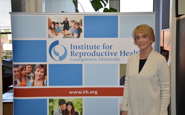 Victoria Jennings stands in office with banner for Georgetown's Institute for Reproductive Health and url displayed beside her