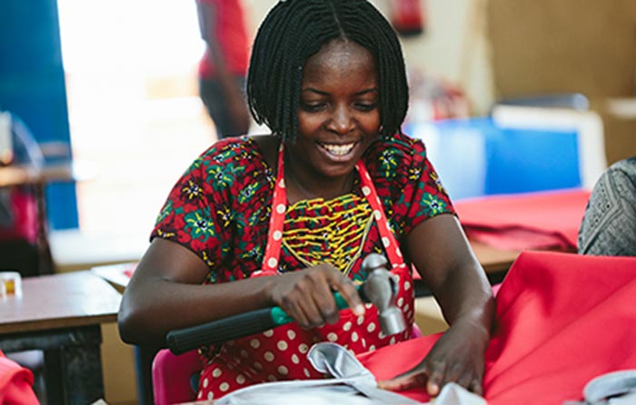 Woman in apron smiles while working on fabric