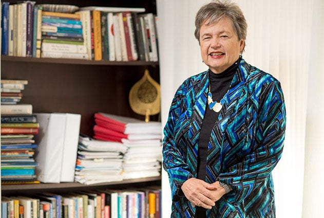 Dean Carol Lancaster smiles next to a bookshelf.