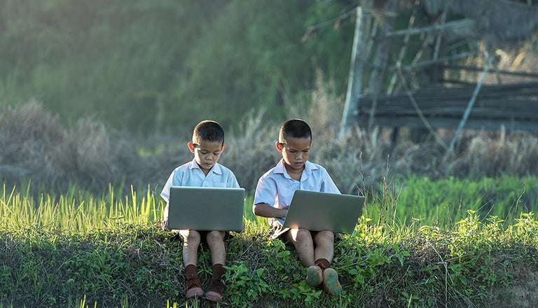 two children in a field with computers