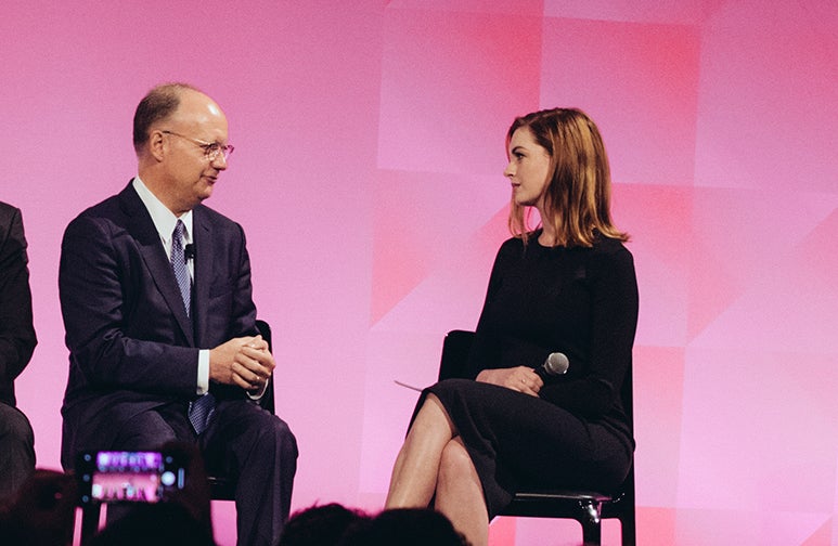 john j. degioia and anne hathaway sit in chairs on a stage