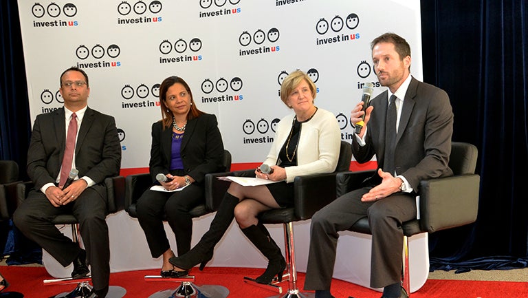 Panelists discuss early childhood innovation on stage in front of sign saying "Invest in Us"