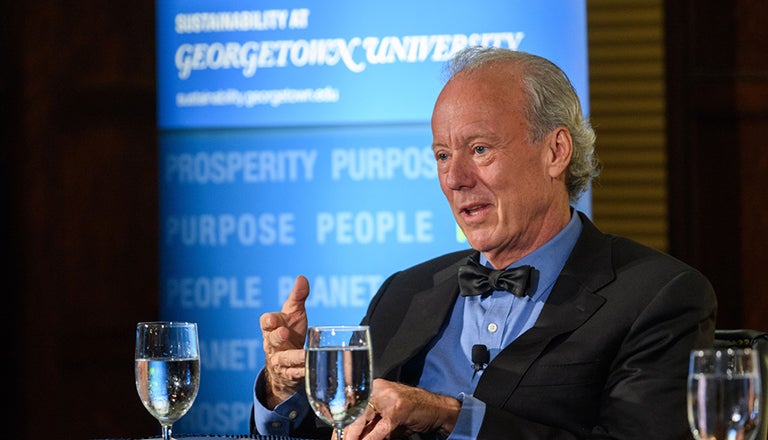 Bill McDonough sits with glasses of water and banner behind him Sustainability at Georgetown Prosperity Purpose People 