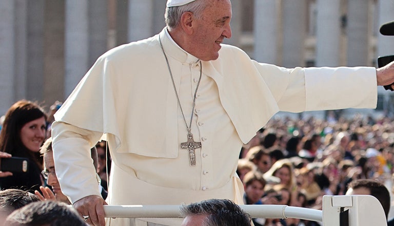 Pope Francis reaches an arm out to the crowd in his popemobile