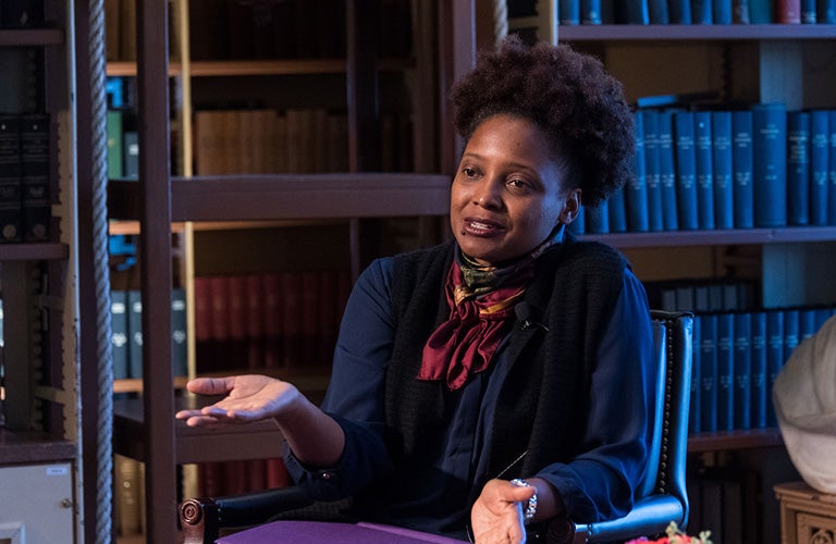 Tracy K. Smith sitting in a chair with bookcases behind her 