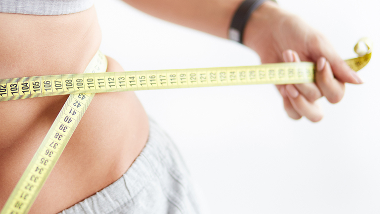 woman wrapping measuring tape around her stomach