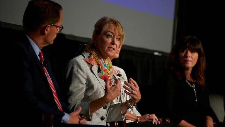 Peggy Compton speaks in Gaston Hall, sitting with other panelists at documentary screening