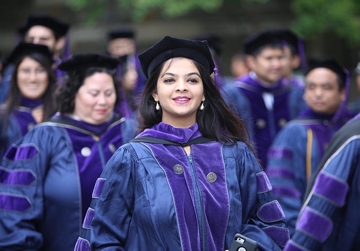 Female Georgetown Law graduate stands in her graduation gown and regalia