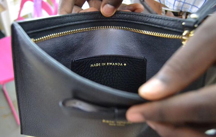 Hands open a handbag to show "Made in Rwanda"