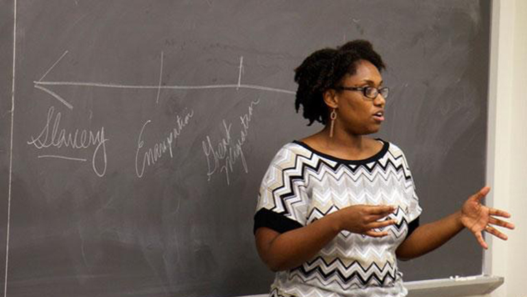 History professor Marcia Chatelain stands in front of chalk board as she teaches class