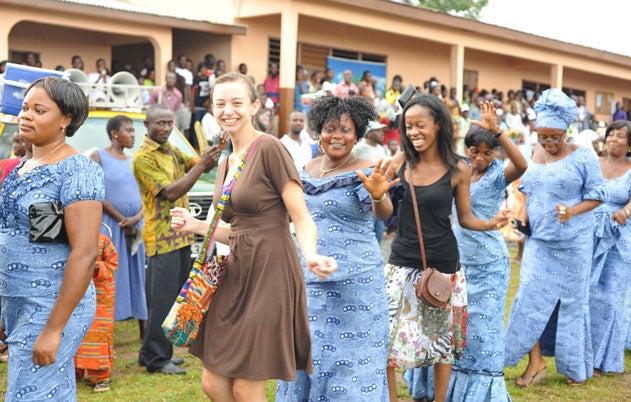 A group of diverse woman in colorful clothing dancing in a line outside