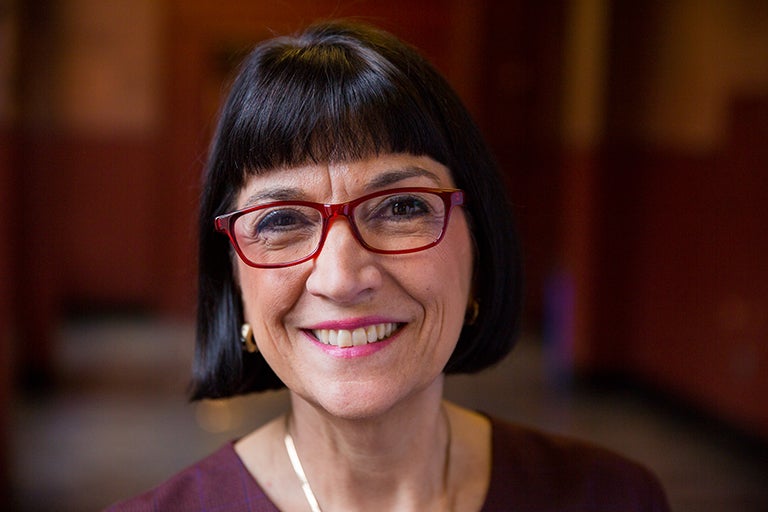 Marie Mattson smiles into the camera with the background of a hallway in Healy Hall in view.