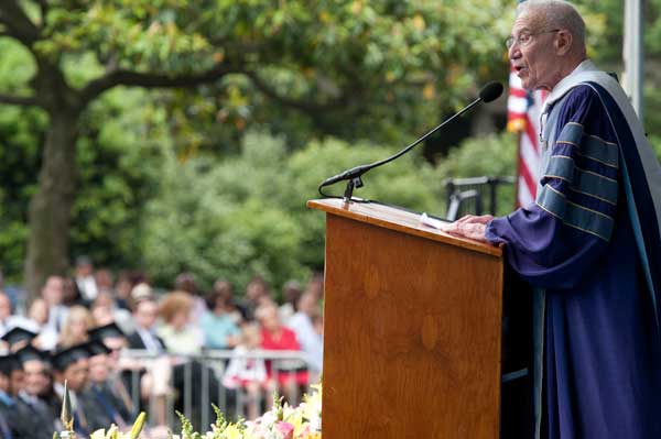 Robert M. Solow speaks behind a podium on stage with Healy Lawn in the foreground