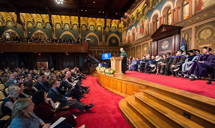 man at podium speaking to audience in Gaston Hall