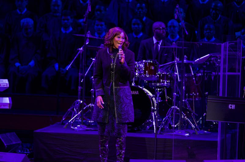 Yolanda Adams signs with microphone in front of Let Freedom Ring! Choir on stage at Kennedy Center