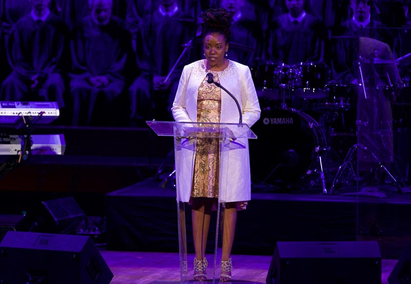 Joy Robertson speaks at a podium on stage at the Kennedy Center