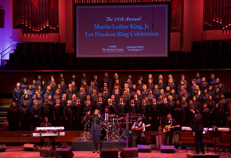 Let Freedom Ring Choir signing on stage at Kennedy Center with graphic projected on screen in background
