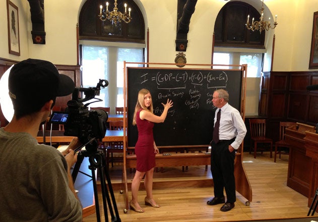 Camera operator filming Linda Oldenski pointing to a portable blackboard with Theodore Moran looking on 