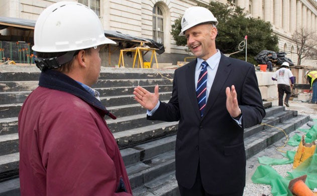 Robin Morey, in a white hard hat, talks with a fellow worker.