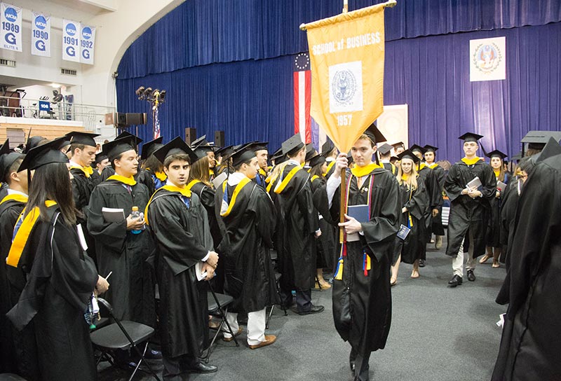 Business school graduates look at the mace as they await the start of their ceremony