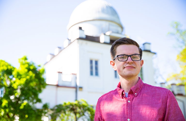 Micah Musser stands outside with the Observatory in the background.