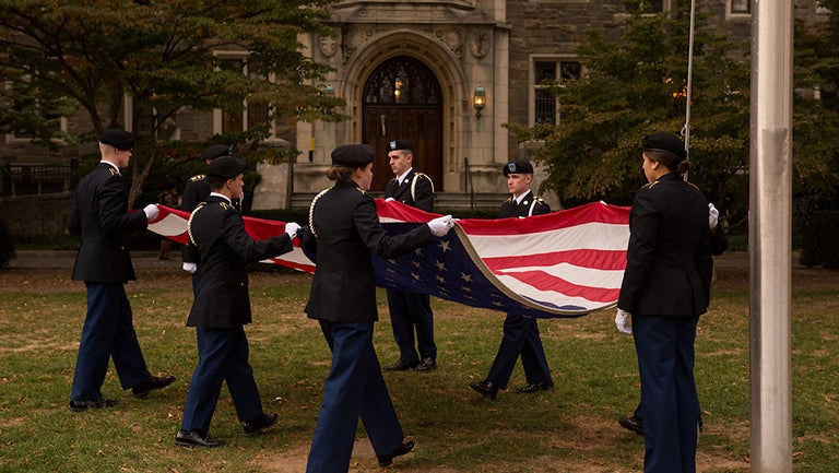 Student veterans fold the American flag at a Veterans Day ceremony on campus