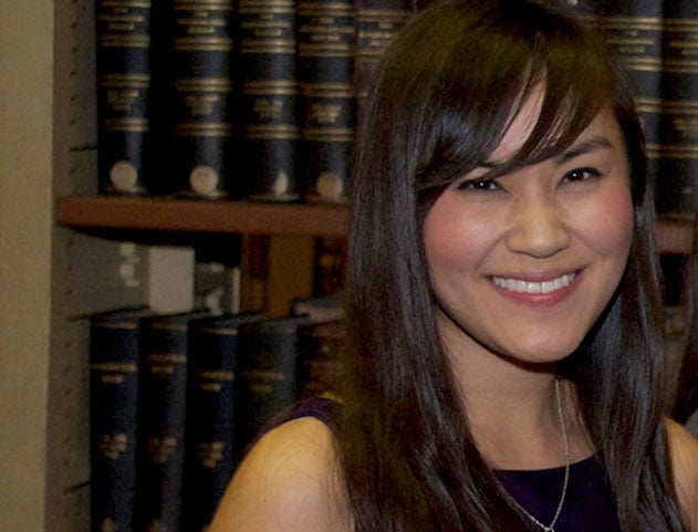 Nhaca Le smiles with books on a bookshelf behind her